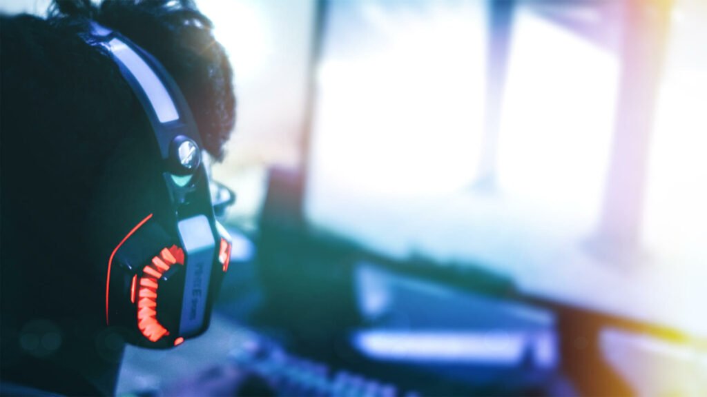 Image of Over the shoulder closeup streamer with gaming headphones in front of blurred screen Web.